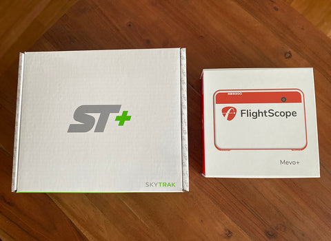 SkyTrak+ and FlightScope Mevo+ in their packaging side-by-side on a table