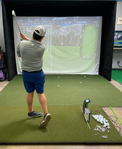 Marc using the SkyTrak+ alongside the GC3 launch monitor in a golf simulator with impact screen