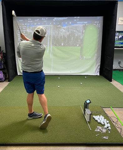 Marc post swing with club raised in an indoor golf launch monitor using the Launch Pro and SkyTrak+ golf launch monitors