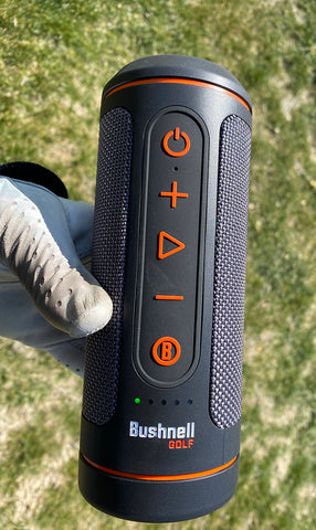 The Bushnell Wingman 2 golf speaker in Marc's hand wearing white golf club on the golf course