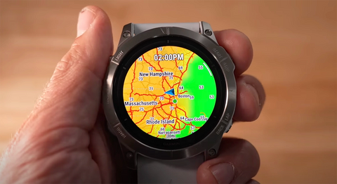 A Garmin watch with the new weather overlay on the display being held in a hand