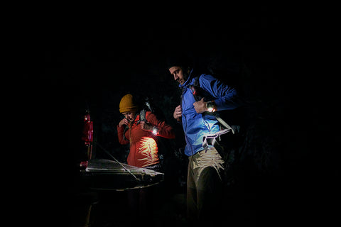 Two hikers getting in the trunk of a car at night wearing Garmin fenix 7 Pro multisport GPS watches with the LED flashlights glowing