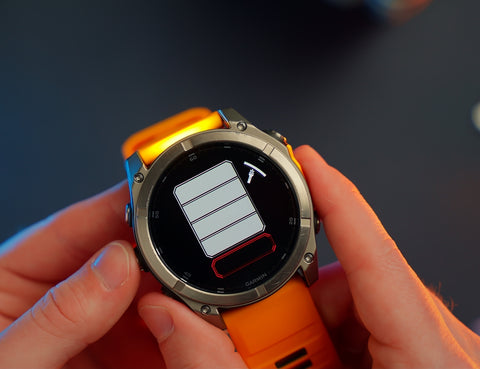 An orange Garmin fenix 8 held by Ryan with the LED flashlight app on the screen