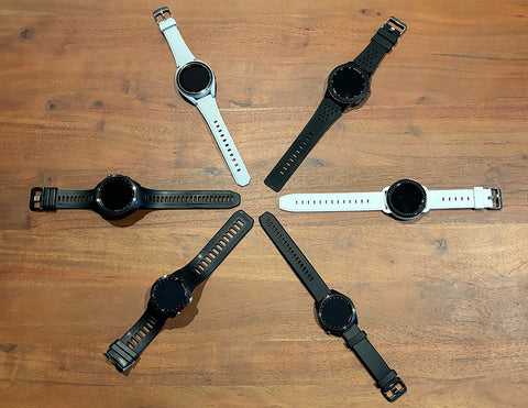 Six black and white golf watches in a star shape on a hardwood floor