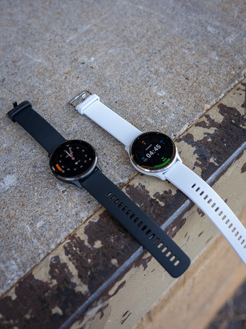 Black and white Garmin Venu 3 watches lying side-by-side on a curb