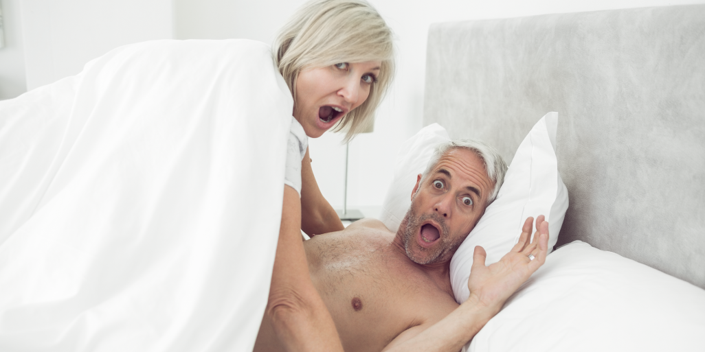 Una pareja se sorprende amorosamente en la cama, demostrando la importancia de la intimidad y la conexión durante la menopausia.