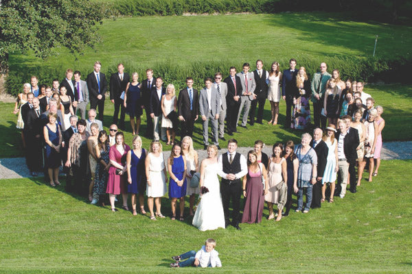 Wedding guests stand in a heart shape for an alternative wedding photo pose