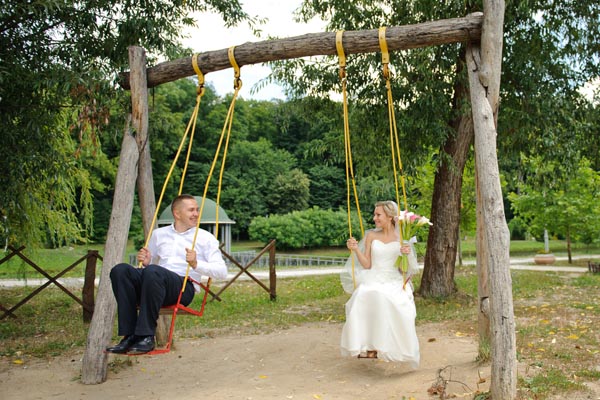 A bride and groom having fun playing on children's swings for an unusual wedding photo