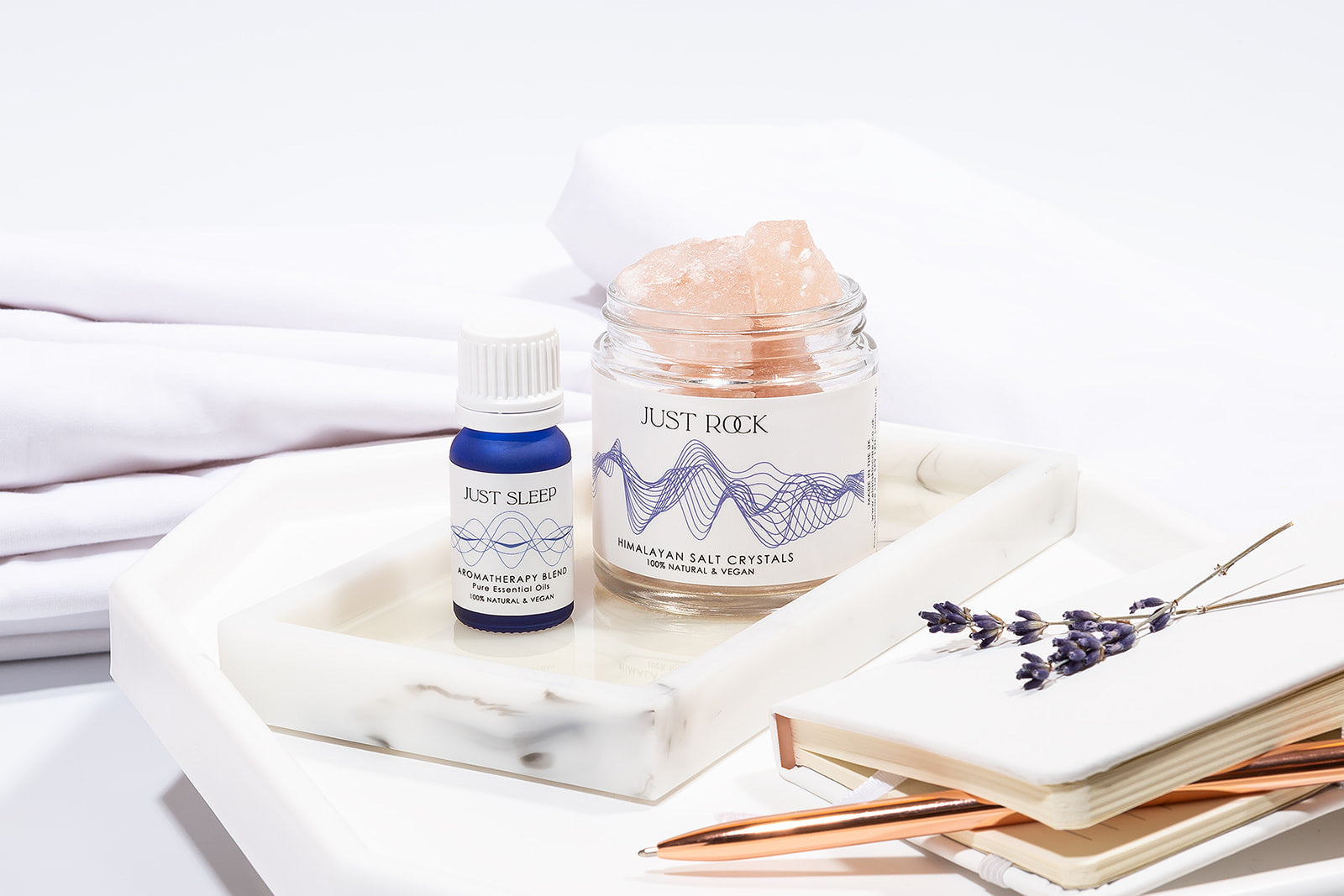 Just Sleep Gift Set - alternative to Aromatherapy Shower Steamers from Elan Skincare, a jar with Himalayan salt crystals together with essential oils blend in a blue 10 ml bottle on a table, lavender placed on a notebook,