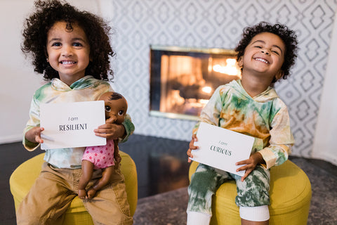 two smiling black and brown kids with affirmation cards