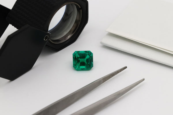 Emerald Gemstone with Jewelers Loupe and Tweezers