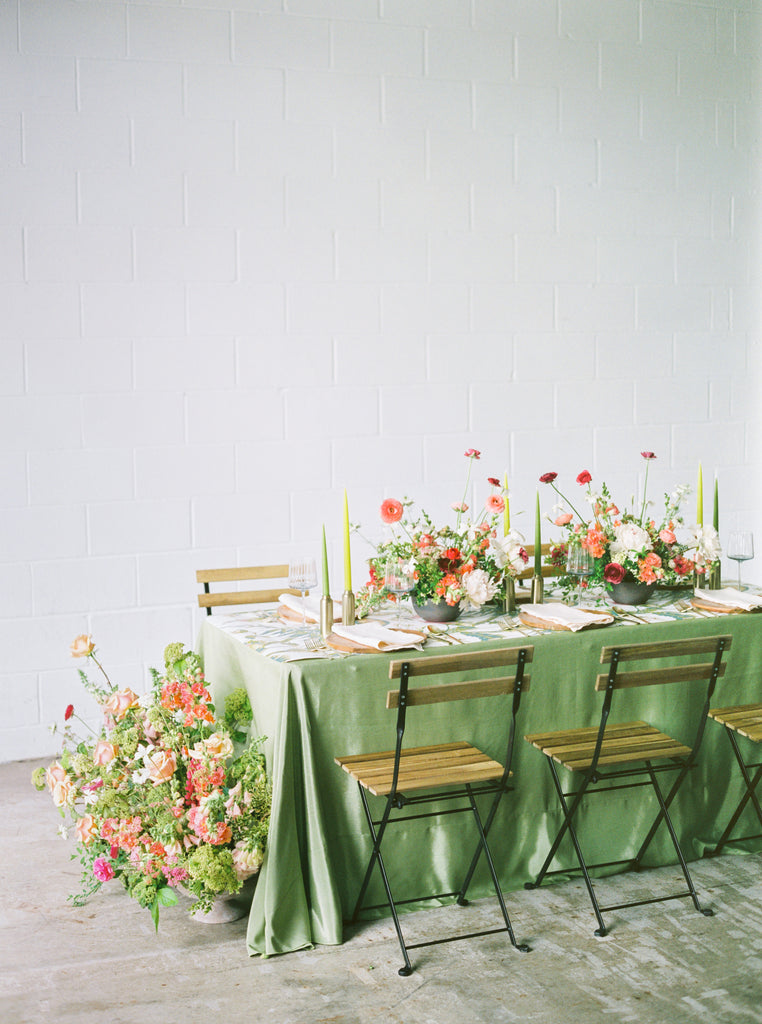 wedding reception table setting with green linens and florals