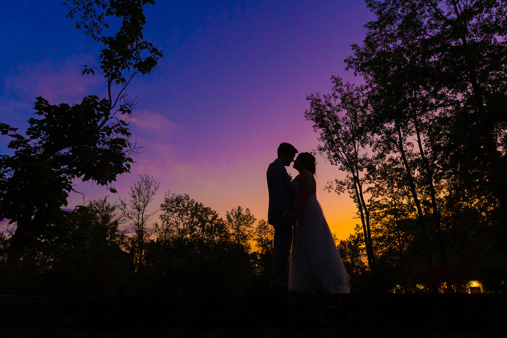 Bride and groom standing outside for wedding photos with the sunset. 
