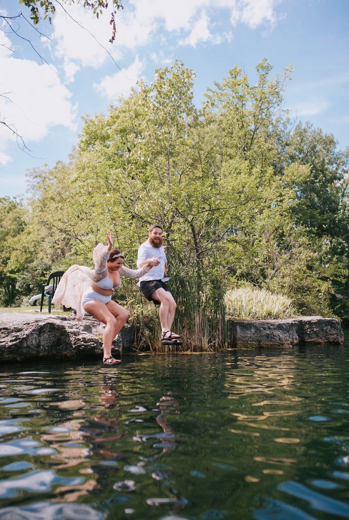 Bride and groom jumping into the water during wedding reception