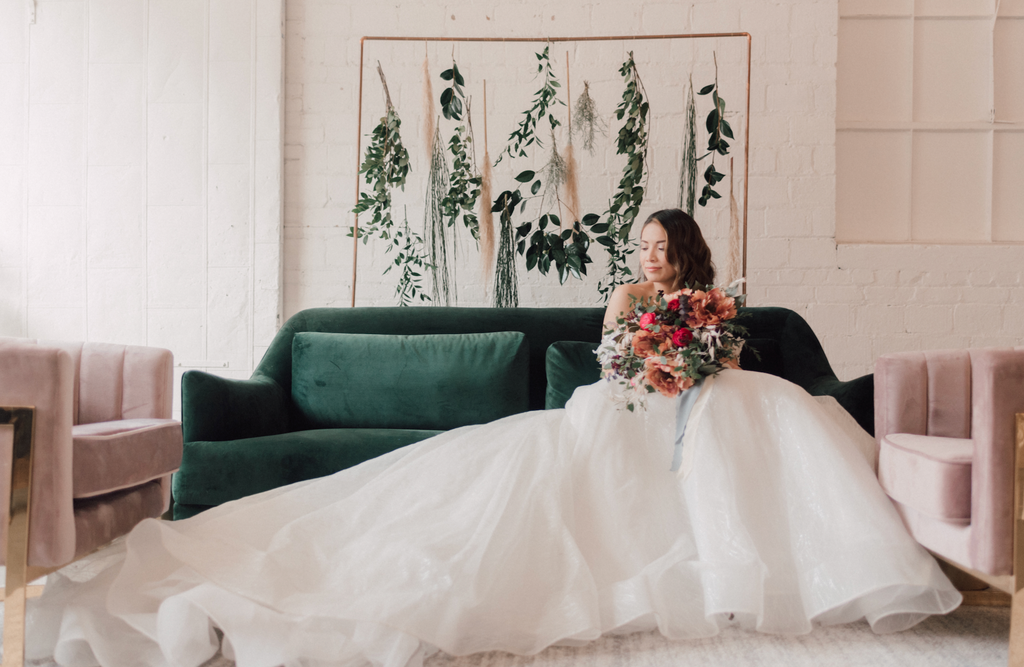 Model sitting on a couch wearing a ball gown wedding dress.
