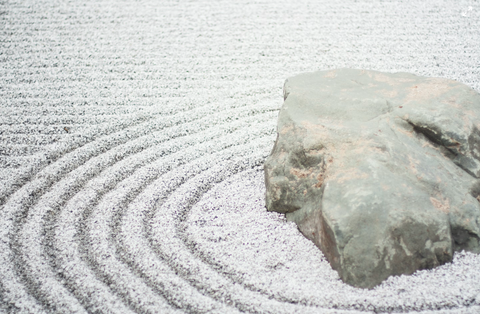 Sand with a circle pattern and a rock in the center of the circles