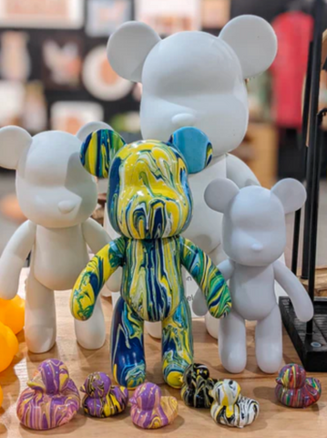 Several white bears next to one bear and several rubber duckies painted with abstract patterns