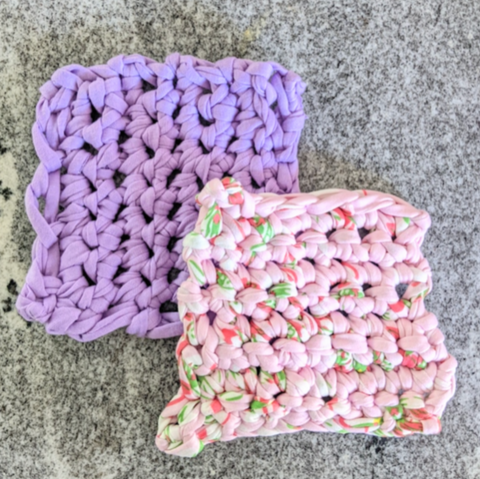 Two square crochet coasters. One is purple and the other is pink with green flecks.