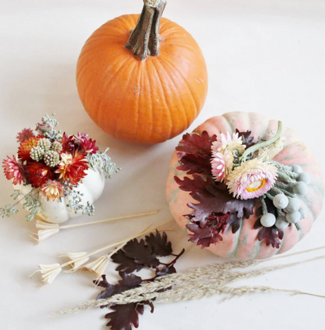 Three pumpkins, two with floral arrangements on top
