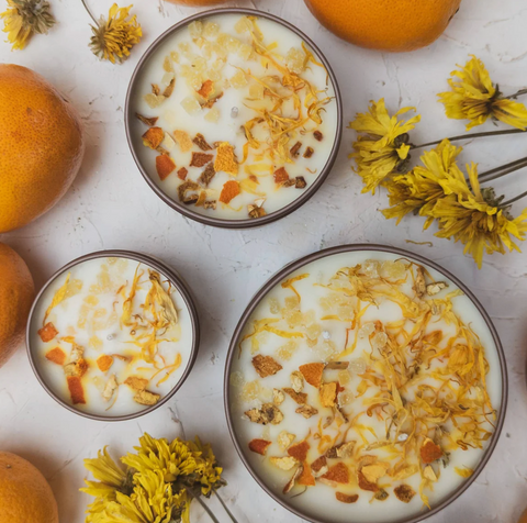 Three candles with oranges and marigold flowers next to them