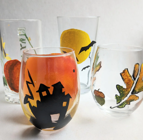 Four glasses with fall-themed patterns painted on them