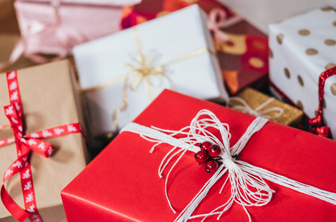 A pile of gifts wrapped in red, white, and brown paper and tied with ribbons