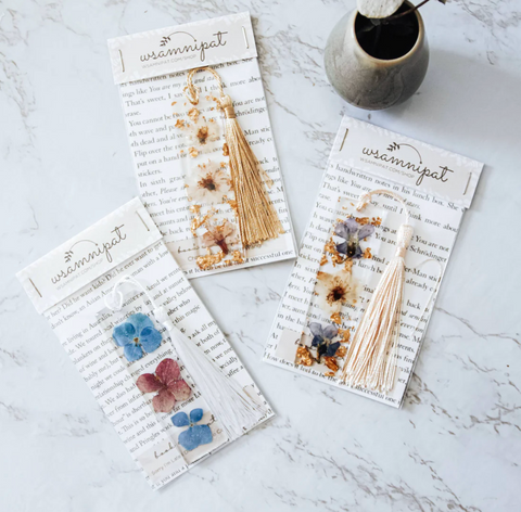 Three flower and resin bookmarks on a white marble background