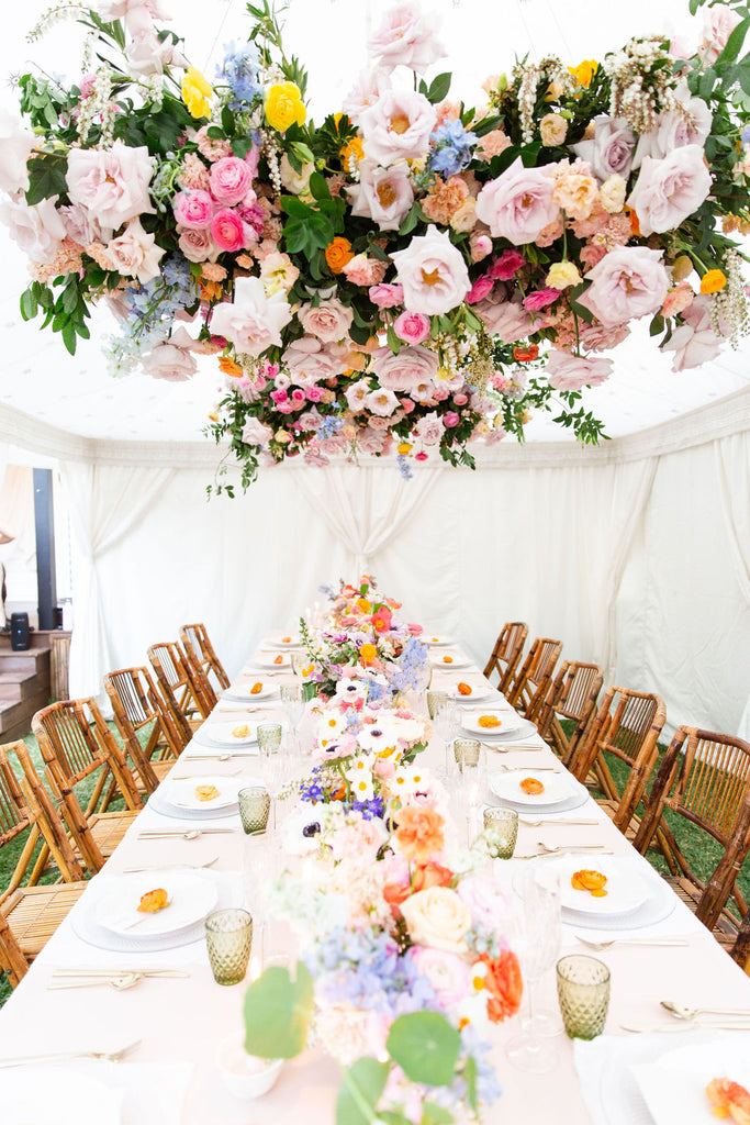 installation florale colorée sans mousse de printemps suspendue au-dessus d'une table à manger remplie de fleurs