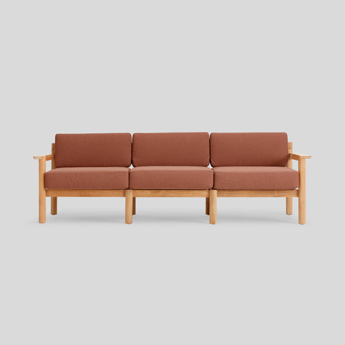 A studio photo of Haven Sofa Sunbrella Rust / Teak Armrest