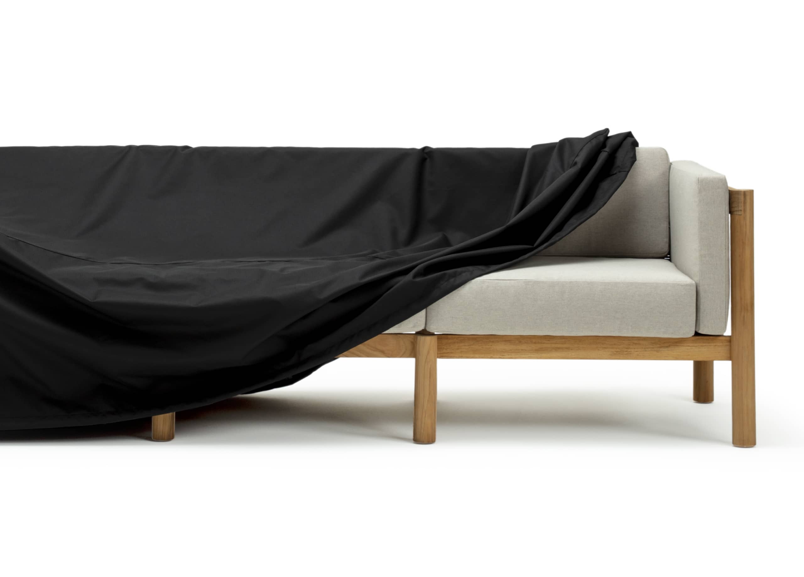 A protective cover being pulled off of an outdoor sofa