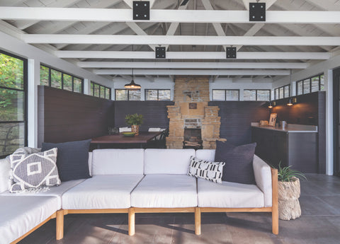 Cozy outdoor sectional with stone fireplace inside a screened in porch