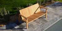 A Neighbor teak Low Chair and ottoman resting on a sunny patio.