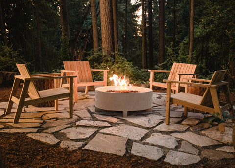 Teak Adirondack chairs surrounding a rounded concrete fire table