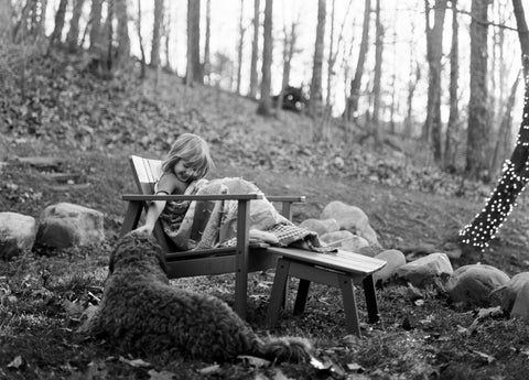 Child wrapped in blanket sitting on a Adirondack chair