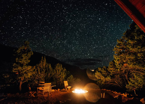Chairs arranged around a rounded fire table underneath a sky full of stars