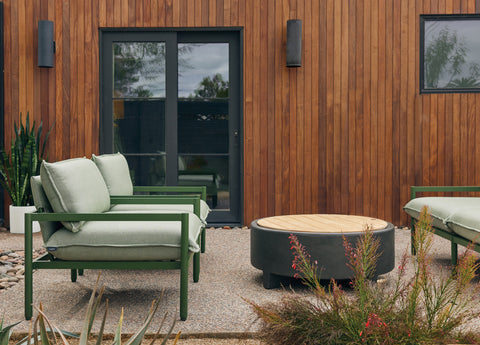 Outdoor chairs with green frame and cushions alongside a fire table