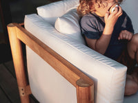 A child sitting in a Neighbor teak outdoor lounge chair