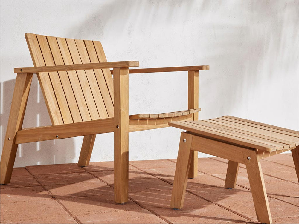 A Neighbor teak low chair and ottoman sitting on a sunny patio