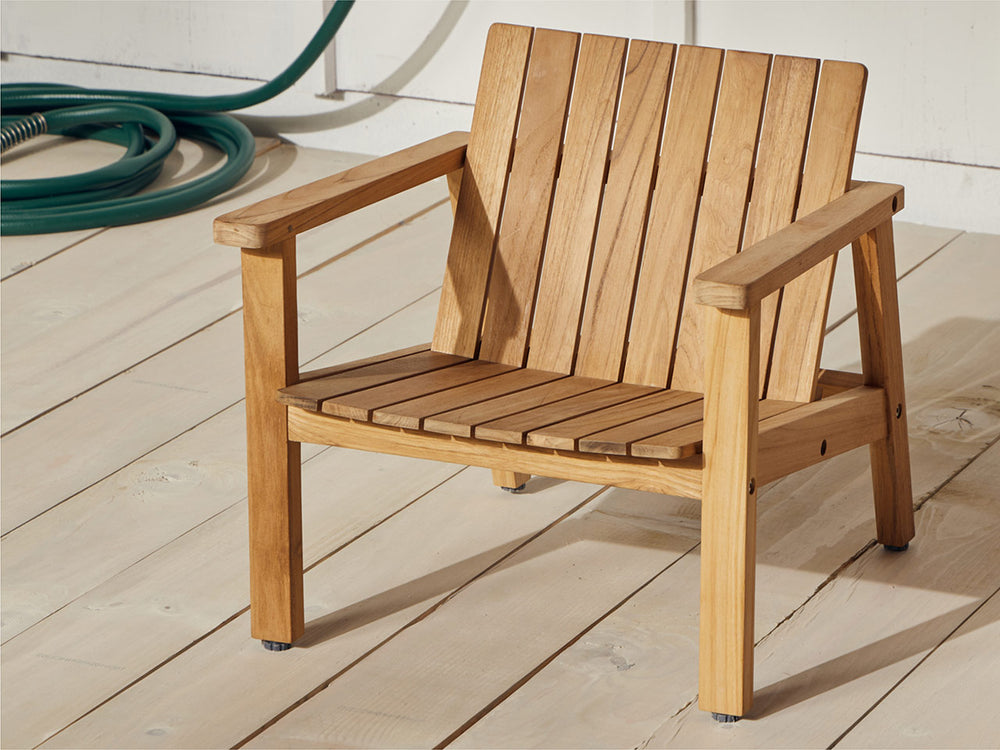 A Neighbor Low Chair Jr. resting on a sunny patio outdoors.