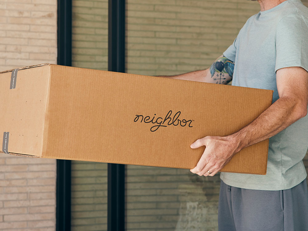 A stack of Neighbor product boxes on a doorstep waiting to be unpacked