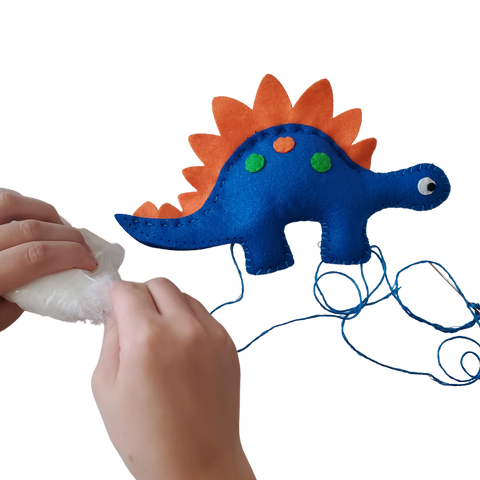 Adding stuffing to a dinosaur stuffed animal