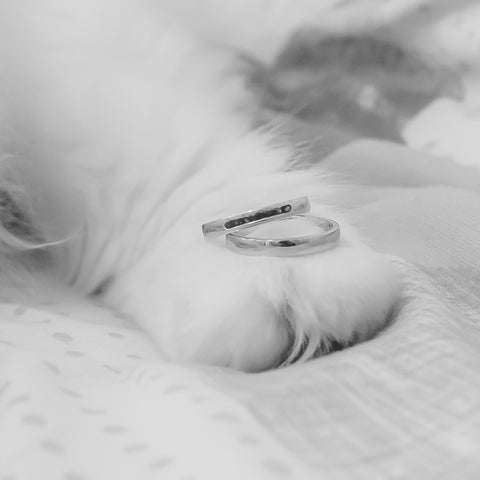 A wedding ring sits on a paw, photographed in black and white