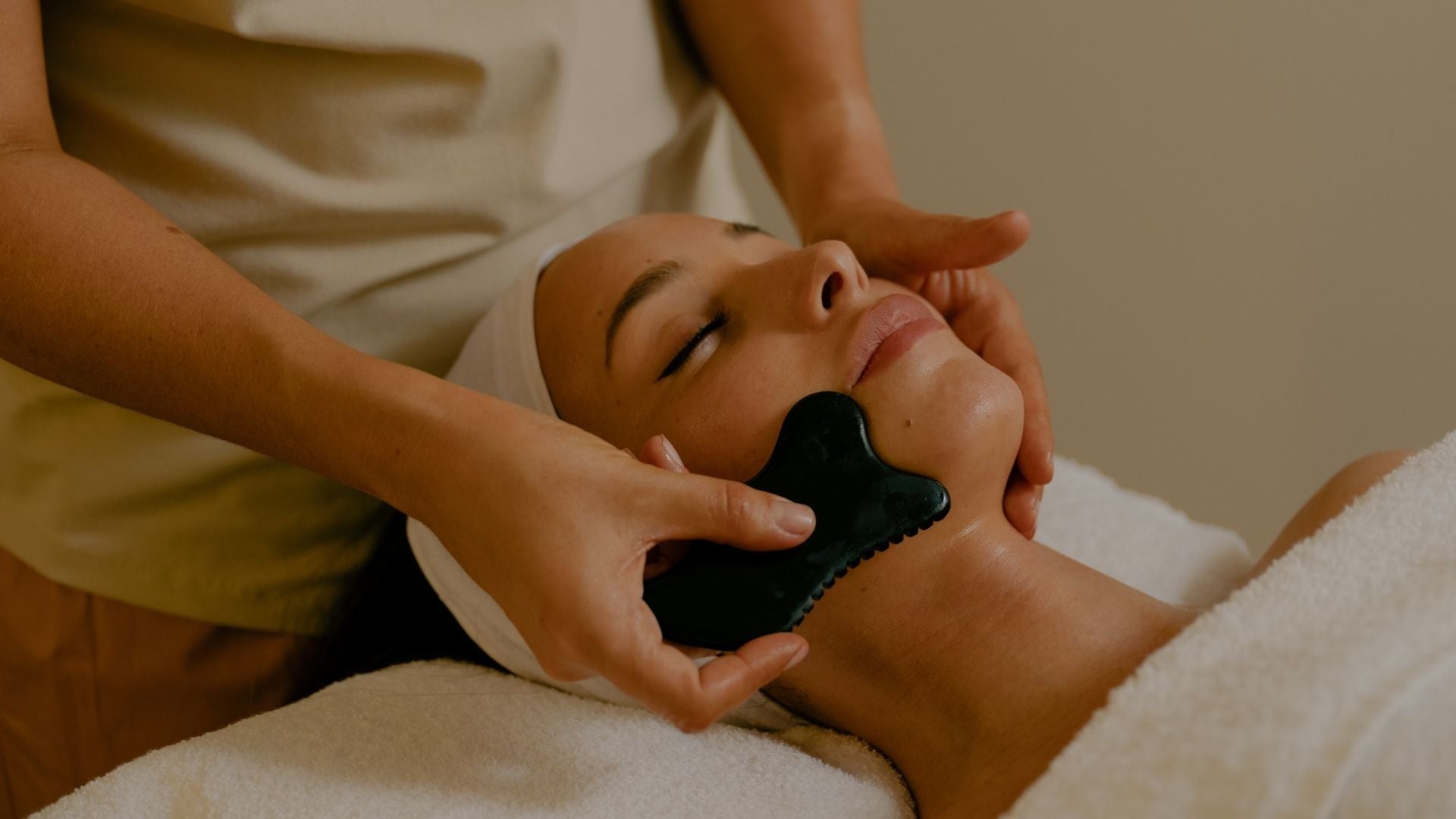 Woman getting a face massage with a Gua sha tool