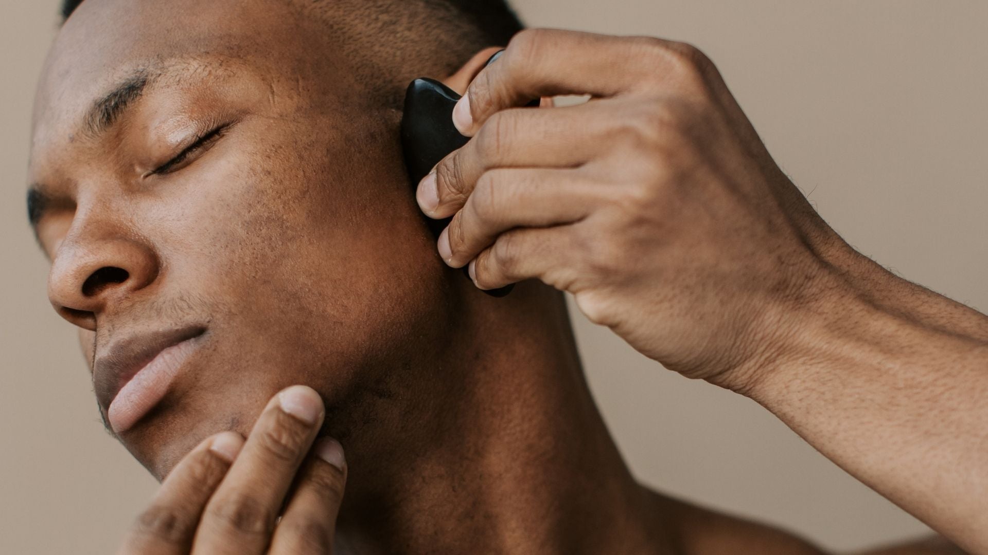 Man using a Gua sha tool on his face