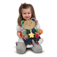 litte girl holding the toddler learning toy for getting dressed 