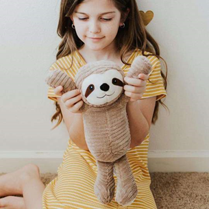 toddler playing with sloth warmies stuffed animal 