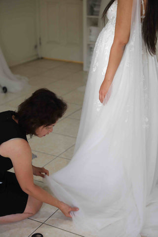 bridal designer fixing wedding dress that bride is wearing