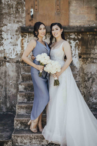 bride and bridesmaid in their dresses on concrete steps