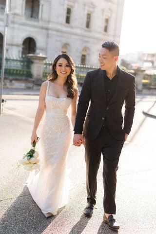 bride and groom holding hands walking together in suit and wedding dress
