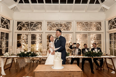 bride and groom hugging at wedding reception in front of cake